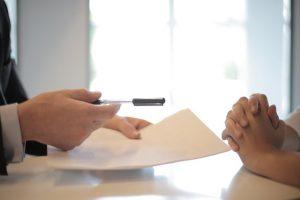 A person handing over a pen to another person to sign the contract after buying a second home in Florida.